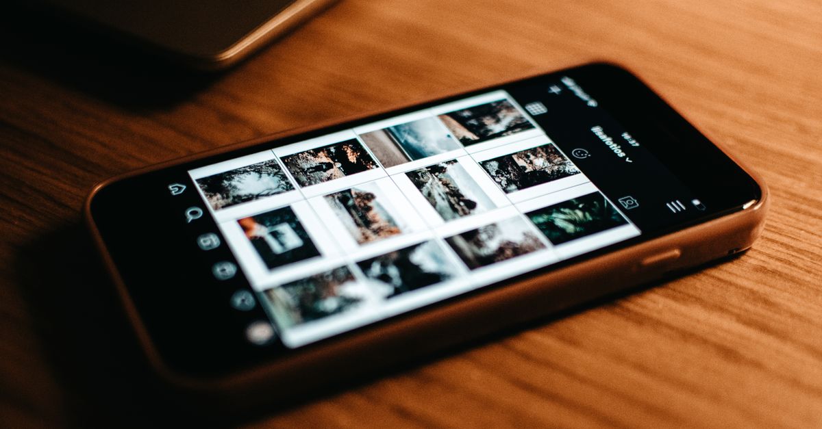 Close-up of smartphone showing photo gallery on wooden desk.